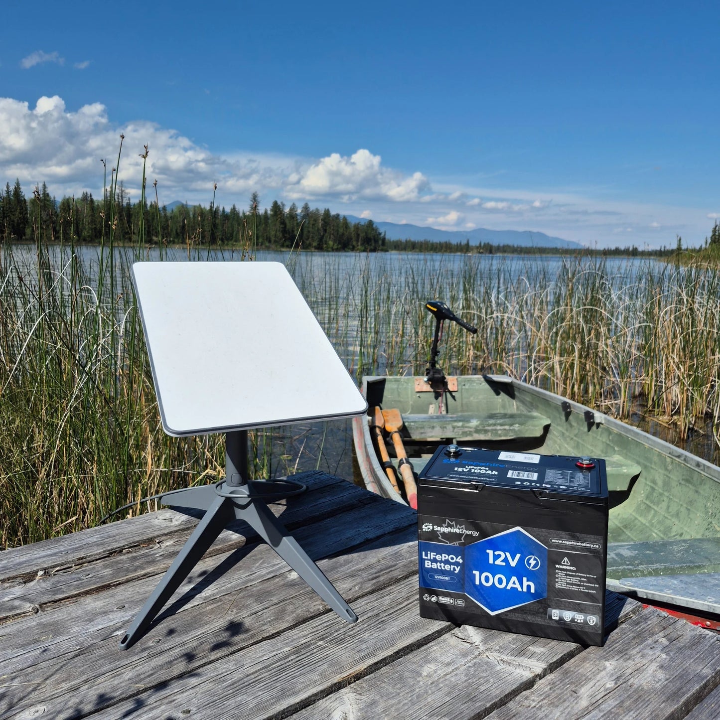 Starlink Dish sitting with a Sapphire Energy Lithium Battery on a dock, with a boat in the background