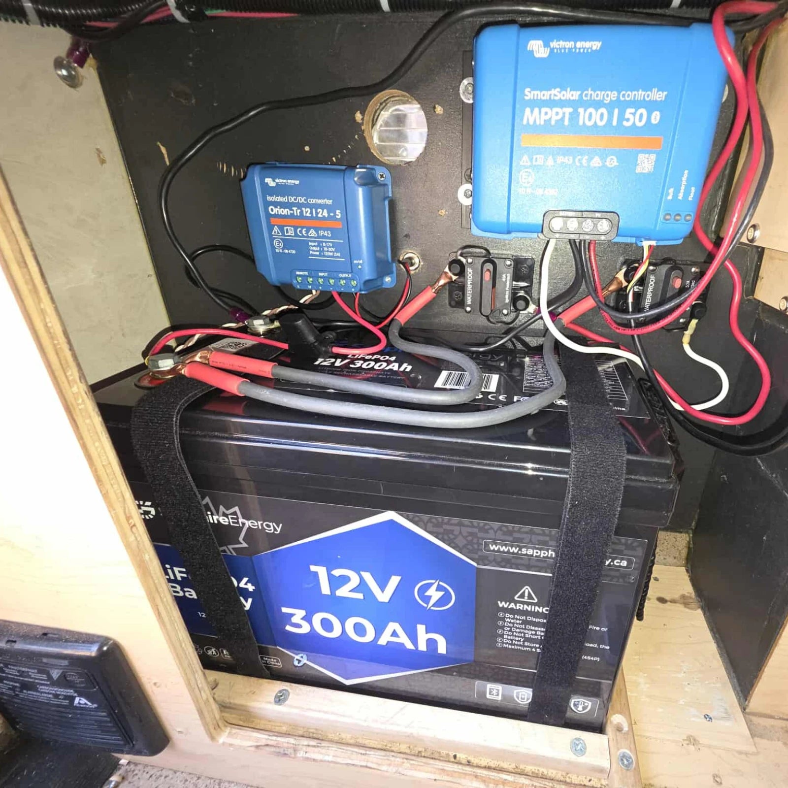 Sapphire Battery and a solar controller setup in a camper on a wooden surface