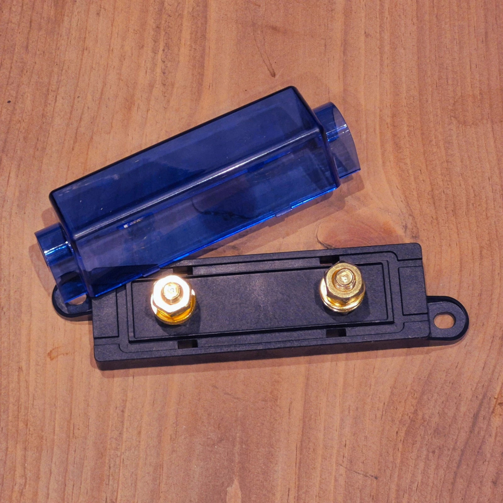 Electrical component with blue cover and gold terminals on a wooden surface