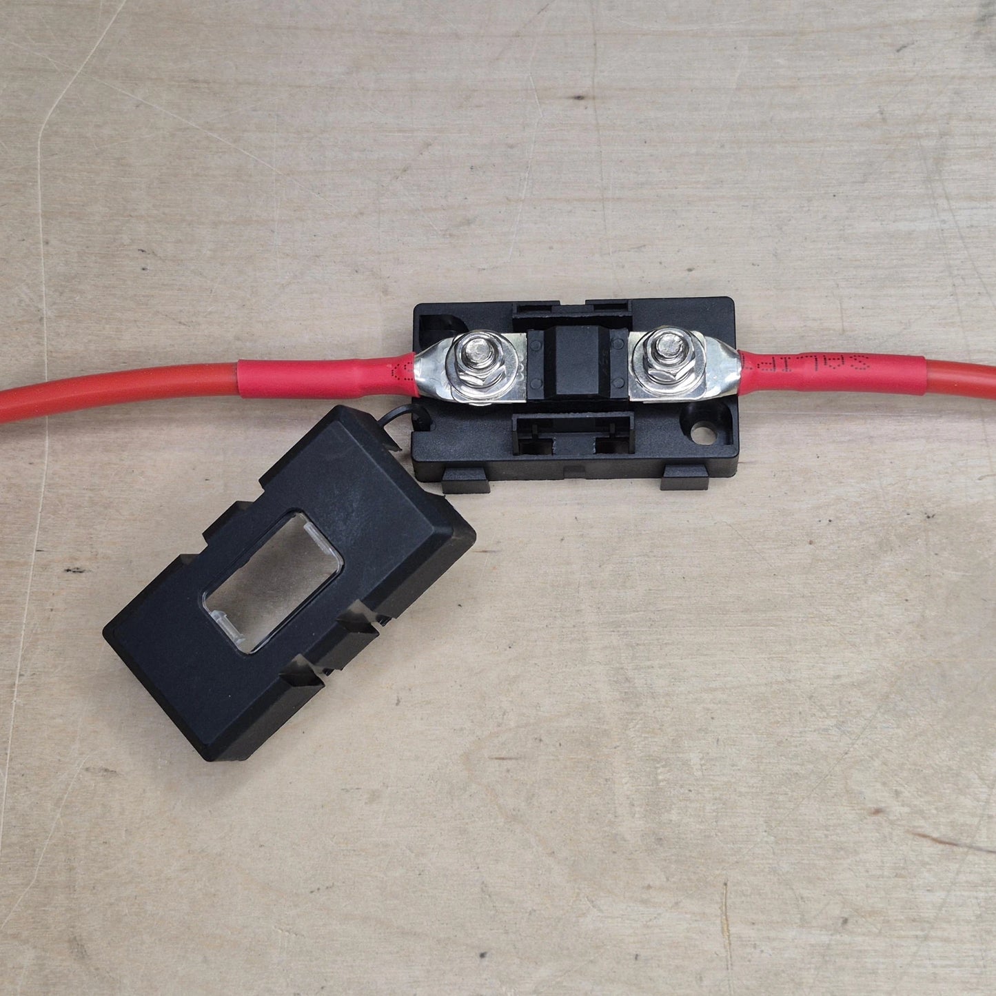 Two red wires connected to a fuse on a black holder.