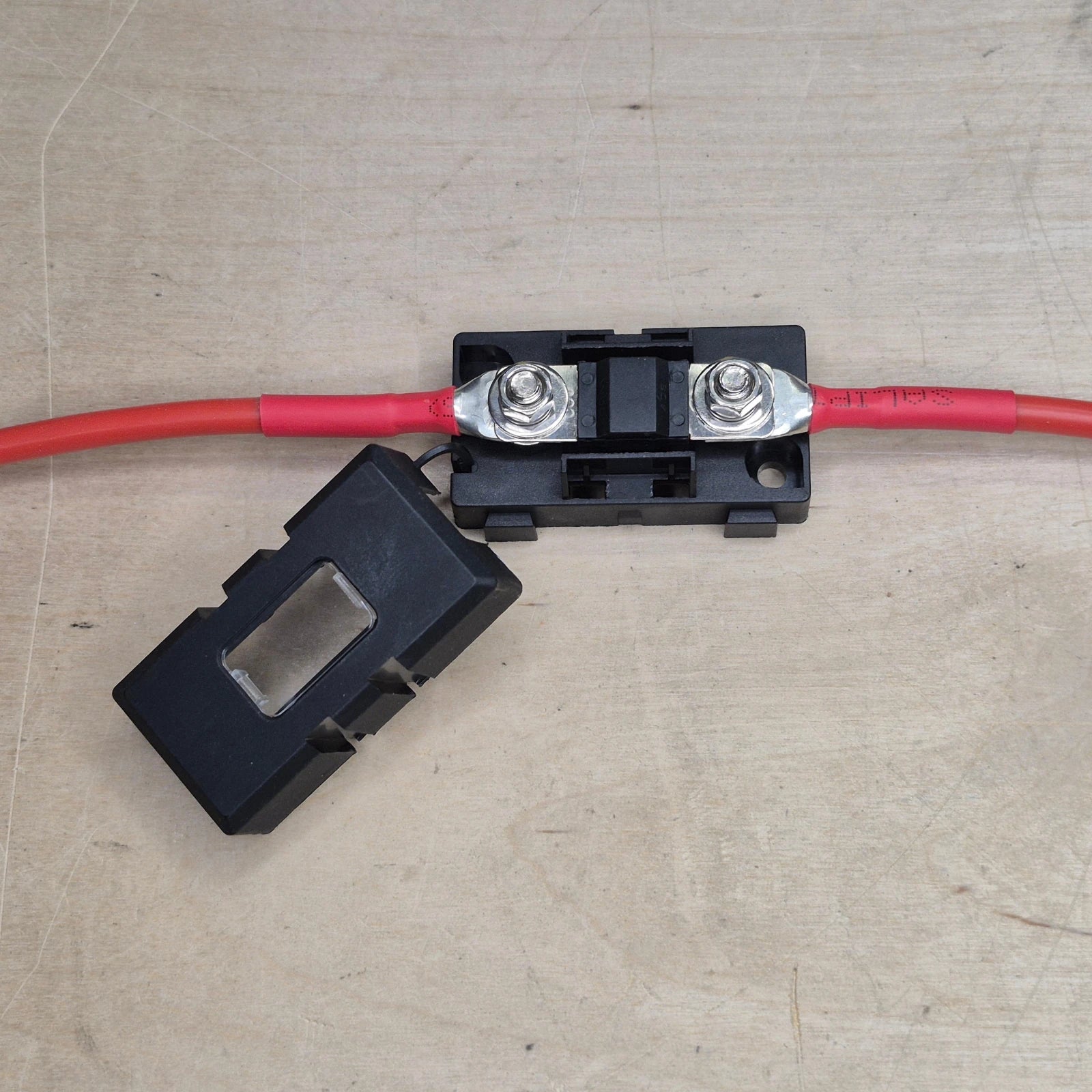 Two red wires connected to a fuse on a black holder.