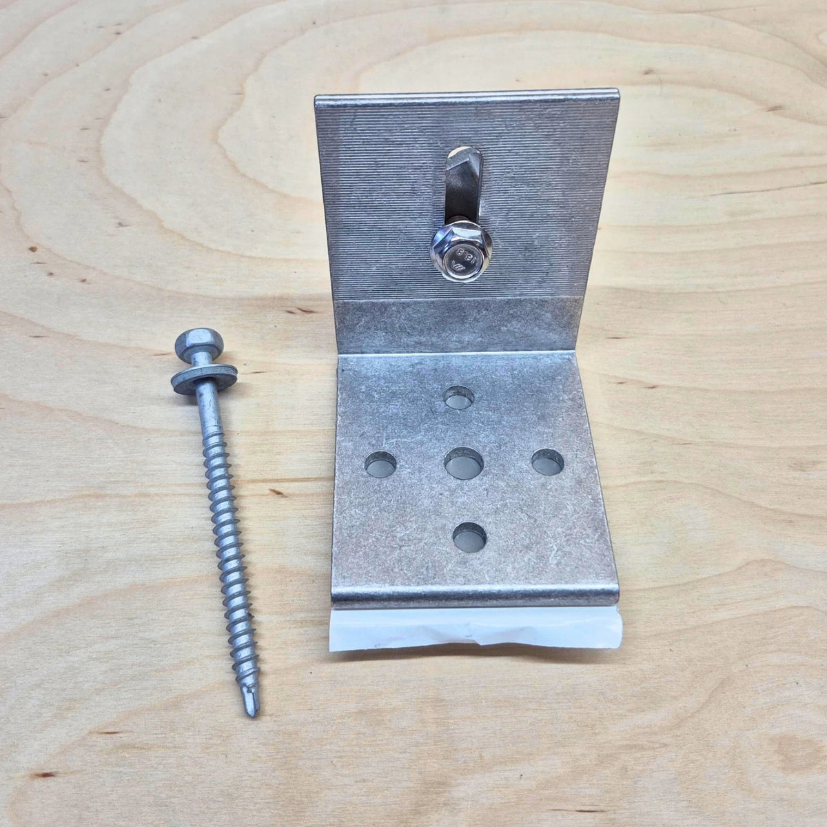 Kinetic Solar Universal L bracket with butyl seal on a wood background.  Shown with included screw and bolt hardware.