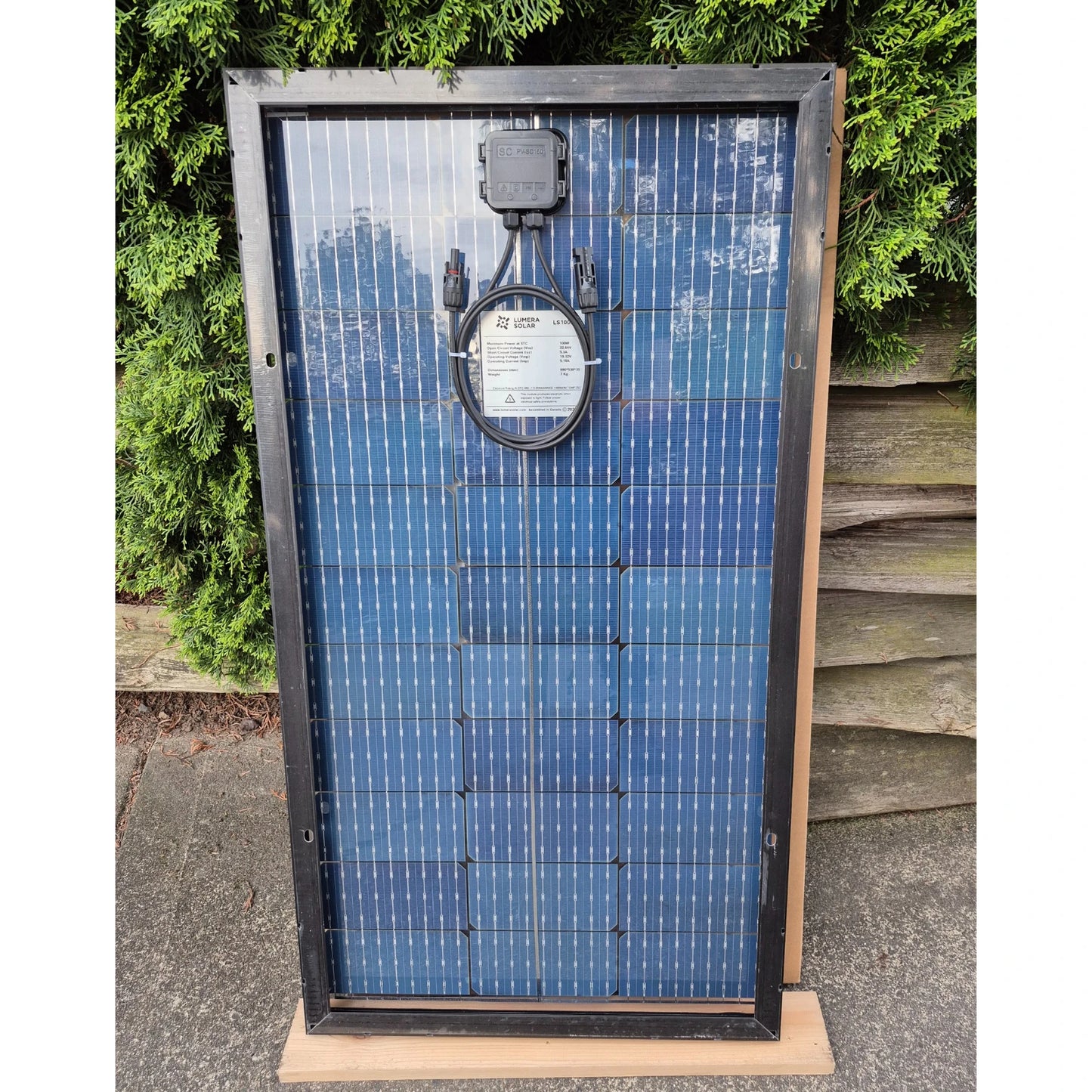 Lumera 100W Solar panel in front of a greenery background