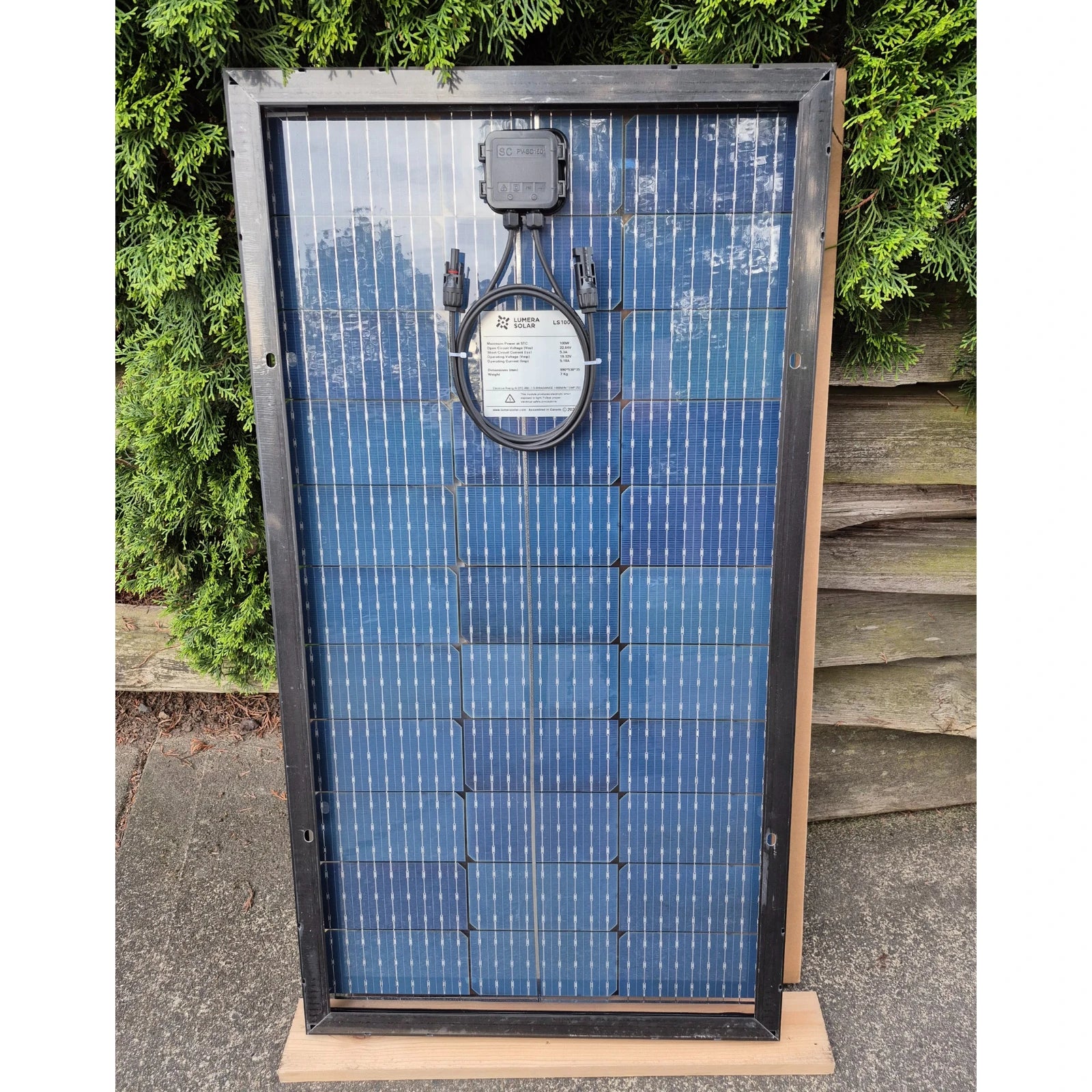 Lumera 100W Solar panel in front of a greenery background