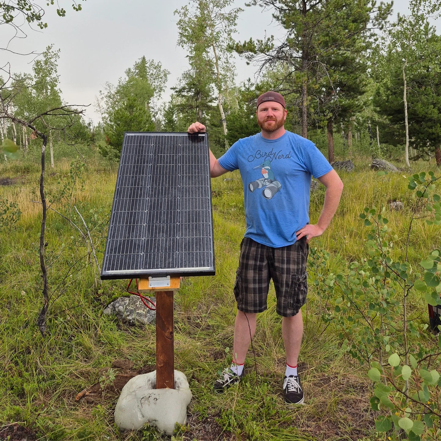 Man holding a solar panel in a forested area