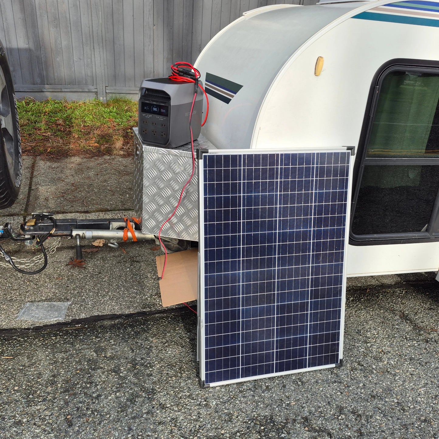 Solar panel attached to an ecoflow portable power station with adapter cable, sitting on the front of a camper trailer 
