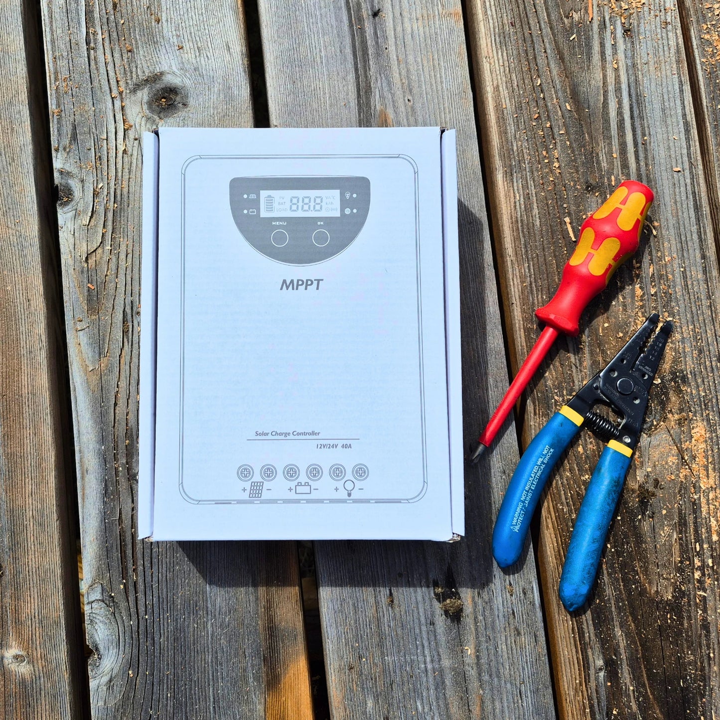 MPPT solar charge controller box with screwdriver and pliers on a wooden surface