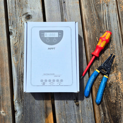 MPPT solar charge controller box with screwdriver and pliers on a wooden surface